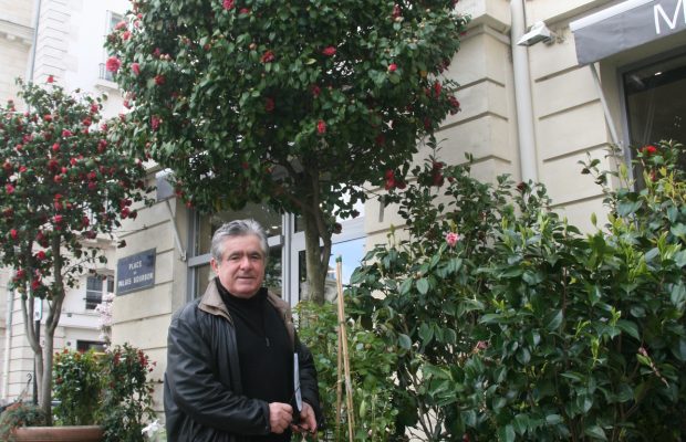 Henri Moulié sous un camélia dont il est fier, devant sa boutique place du Palais Bourbon à Paris